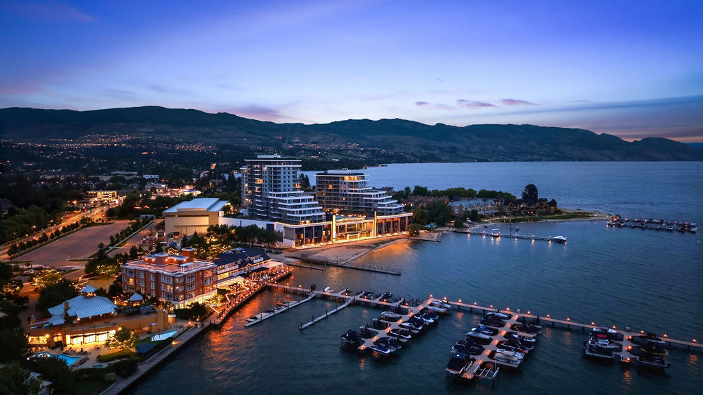 Aerial view of Aqua Waterfront Village towers and marina on Okanagan Lake at dusk